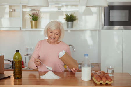 Smiling retired woman enjoying cooking at homeの写真素材