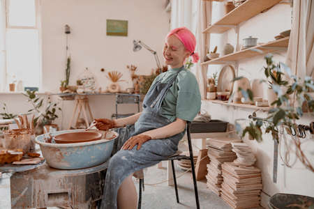 Cute potter creating ceramic bowl on circle in workroomの写真素材