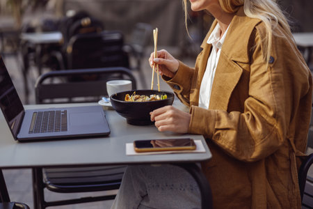 Woman holding chopsticks over dish at cafeの写真素材