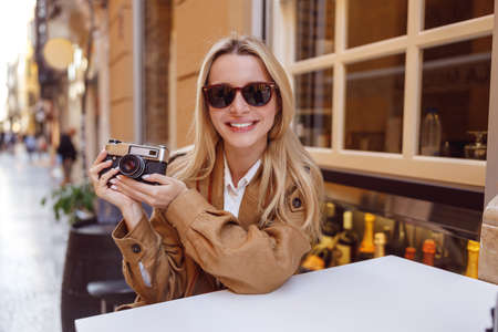 Portrait of blonde lady in sunglasses holding photo cameraの写真素材