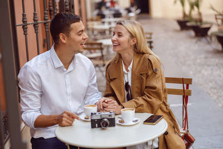 Couple laughing while sitting at cafe table during dateの写真素材