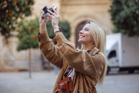 Attractive woman holding retro camera while standing on streetの写真素材
