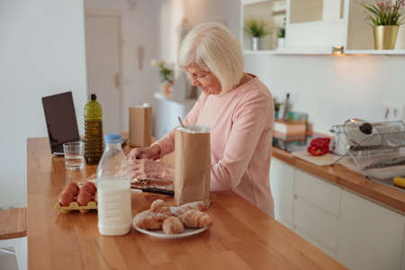 Elderly female molding homemade baking in kitchenの写真素材