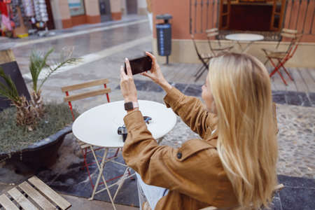 Close-up of woman holding phone and taking picture of buildingの写真素材