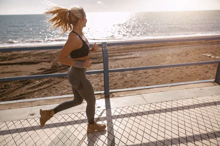 Sporty young female enjoying jogging along beautiful coastの写真素材