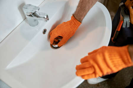 Male plumber hands repairing sink in bathroomの写真素材