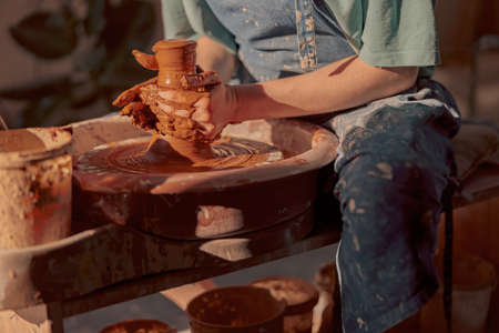 Woman potter creating plate on pottery wheel indoorsの写真素材
