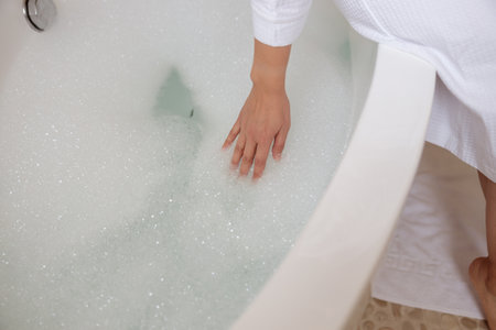 Lady is testing temperature of water in bathroom