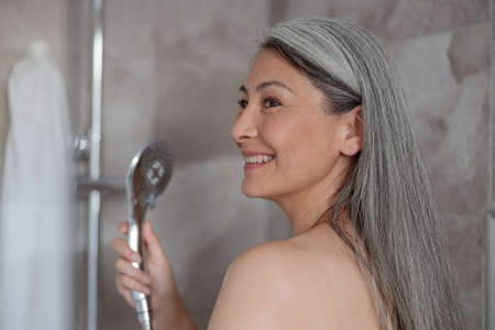 Portrait of smiling Asian woman taking showerの写真素材