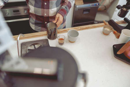 Photo of male barista hands holding pitcher with milkの写真素材