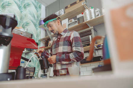 Portrait of man barista whipping milk in pitcherの写真素材