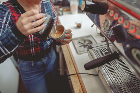 Young barista woman adding milk to espressoの写真素材