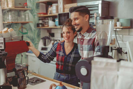 Young lady and man barista standing near the coffee machineの写真素材