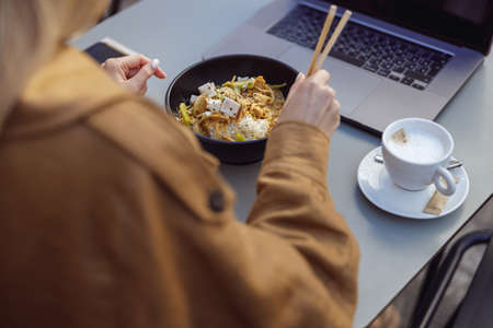 Female enjoying meal while sitting at table in outdoor cafeの写真素材