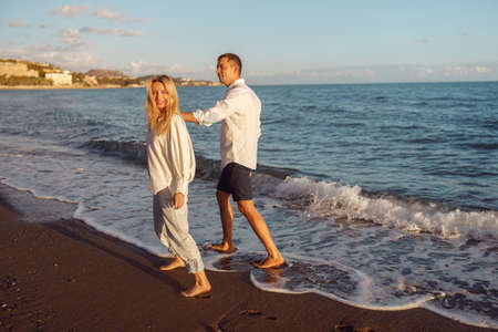 Full-length photo of happy couple walking along the beachの写真素材