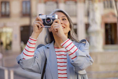 Woman photographer taking photo at city centerの写真素材