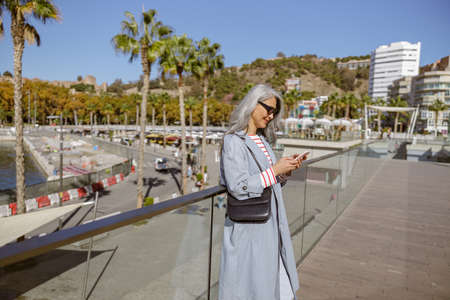 Photo of charming woman using smartphone in cityの写真素材