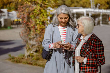 Stylish mature woman using phone at modern cityの写真素材