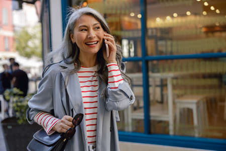 Photo of charming woman using smartphone outdoorsの写真素材