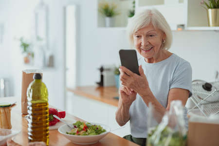 Photo of elderly lady with phone indoorsの写真素材