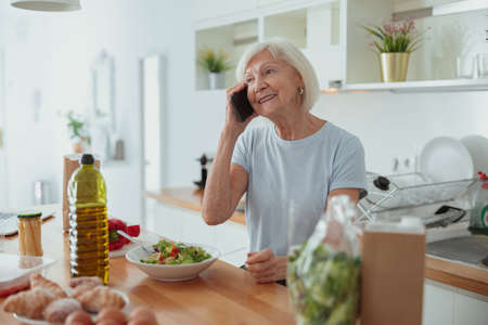 Retired woman communicating at cozy home kitchenの写真素材