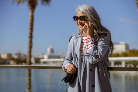Photo of charming lady using smartphone outdoorsの写真素材