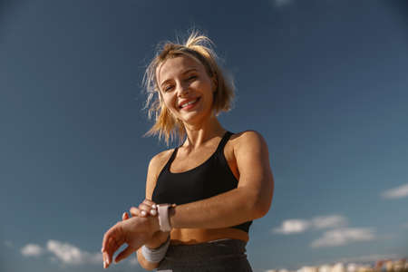 Smiling young sportswoman doing warm-up exercise outdoorsの写真素材