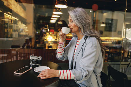 Modern Asian lady relaxing at street cafeの写真素材