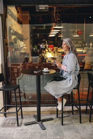 Confident mature woman sitting at urban cafeの写真素材