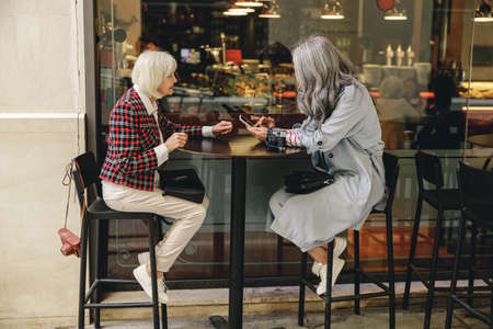 Two happy women having coffee in cafeの写真素材
