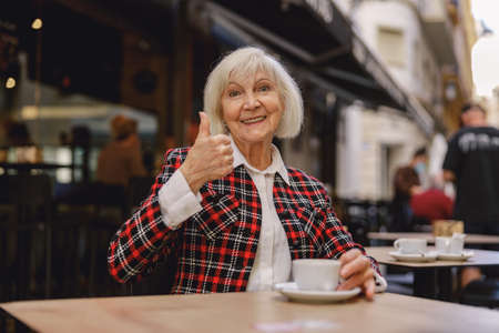 Positive pensioner female having coffee at cafeの写真素材