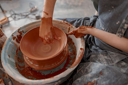 Skillful craftswoman creating earthen bowl on circle in art studioの写真素材