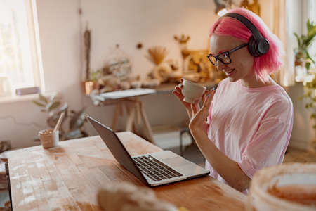 Young craftswoman with laptop computer in art studioの写真素材