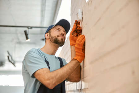 Bearded man checking security camera on the wallの写真素材