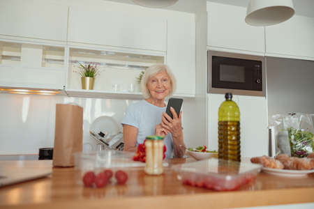 Photo of elderly lady with cell phone indoorsの写真素材