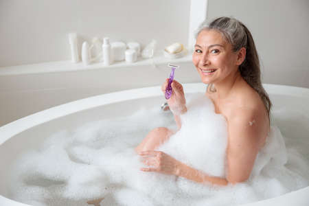 Happy woman preparing to remove leg hairの写真素材