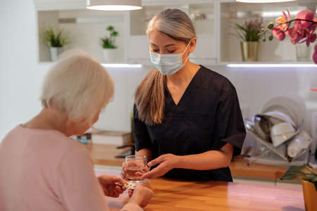 Medical practitioner helping elderly woman at homeの写真素材