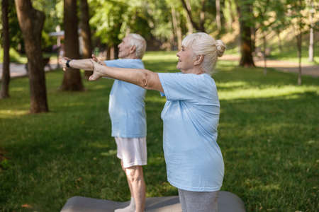 Sportive senior lady with partner train together standing on lush lawnの写真素材