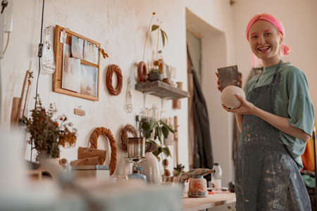 Positive female artisan having ceramics in workshopの写真素材