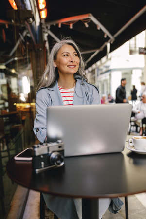Confident Asian woman sitting at urban cafeの写真素材
