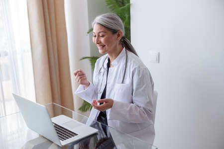 Poprtrait of happy medical specialist lady working on laptopの写真素材