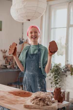 Female pottery artist preparing clay for molding in workroomの写真素材