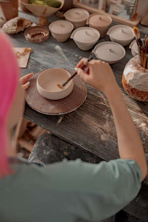 Young ceramist working with clay crockery in workroomの写真素材