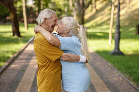 Sportive senior wife and husband embrace standing on road in parkの写真素材
