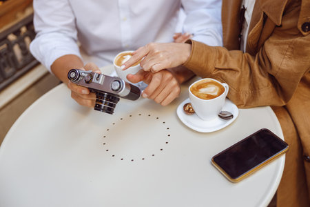 Close-up of male hands holding photocamera over tableの写真素材