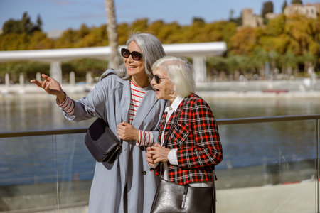 Female friends having conversation on promenade by seaの写真素材