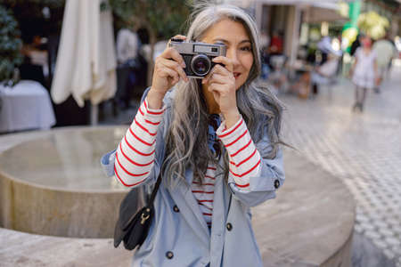 Woman photographer taking photo at city centerの写真素材