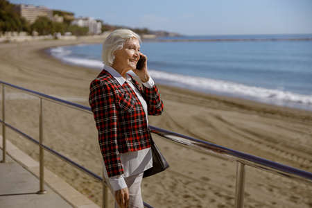 Urban elderly lady relaxing outdoors by seaの写真素材