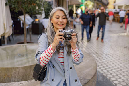 Enthusiastic woman with camera taking photos on streetの写真素材