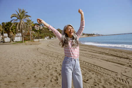 Cheerful urban woman relaxing outdoors by seaの写真素材